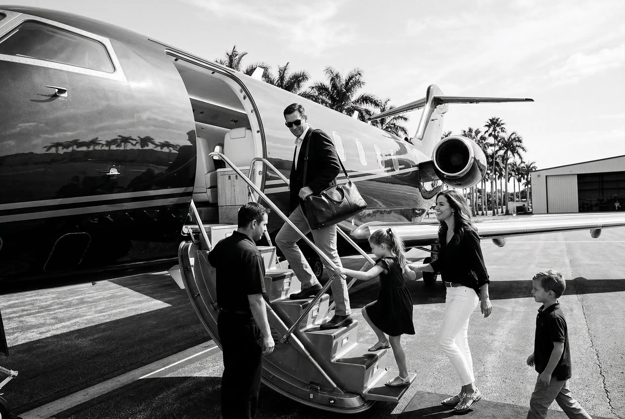 Family boarding a private jet via airstairs on a sunny ramp